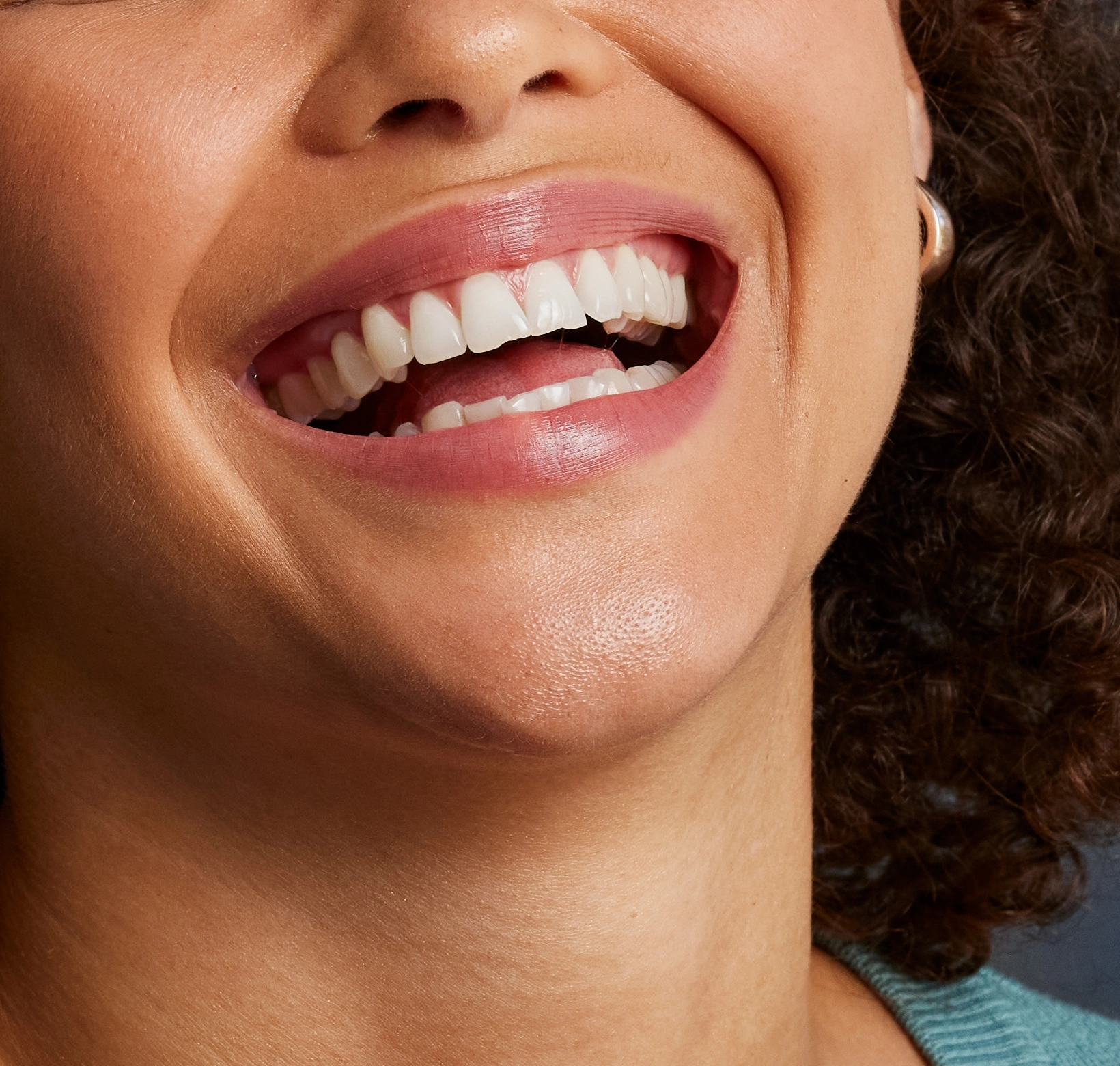 Detalhe do sorriso natural de uma mulher na campanha visual da marca