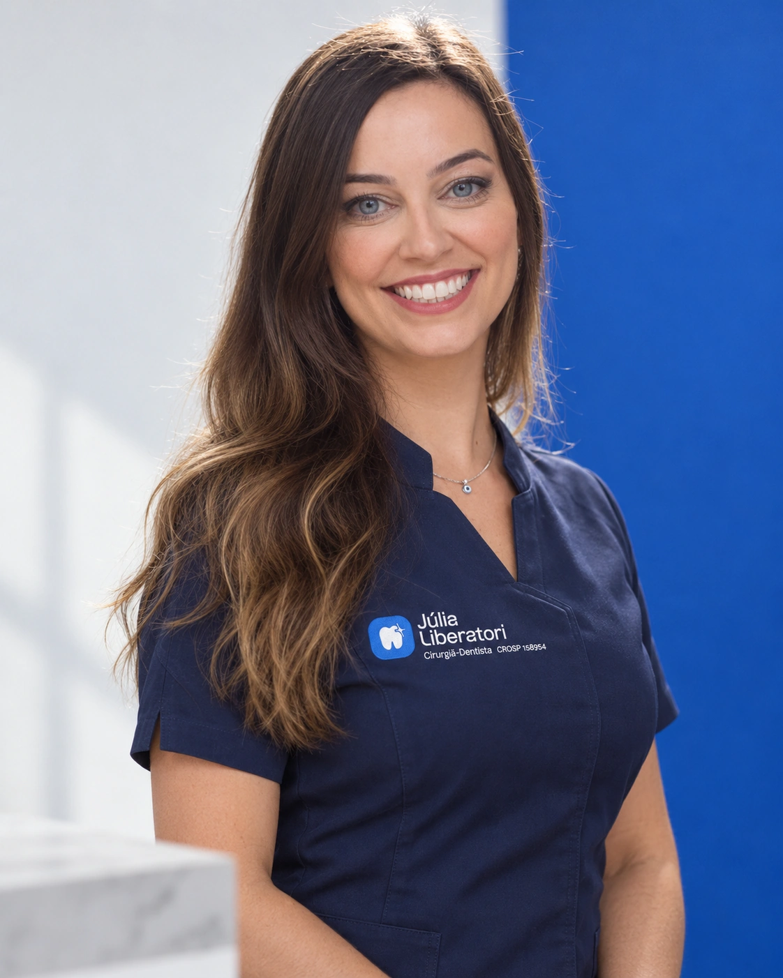 Retrato editorial de Júlia Liberatori com uniforme odontológico azul-marinho e logo bordado no peito
